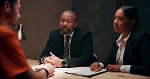 Police, criminal and question in interrogation room for investigation, discussion or arrest. Law enforcement, diversity and people in conversation with suspect for justice, interview or crime
