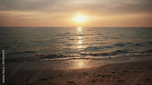 Sea waves during sunrise. Waves crashing on beach, sea wave on the sand close-up, sunset, dawn over the sea.