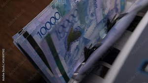 Closeup currency counting machine counting tenge bills. Cash counting equipment. National currency of the Republic of Kazakhstan.