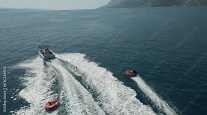 Aerial. Fast moving boat pulling tubes on a sea. Tubes, towables