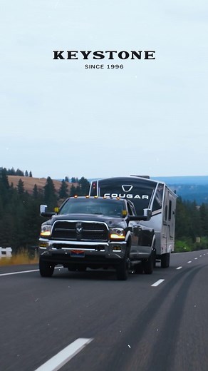 The 2026 Cougar Half-Ton 29RLP features a Rear Living Room and a large utility pantry located behind the TV, across from the Trifold and Theater Seating. It also has a King Bed in the master suite, and a 36" x 36" shower in the bathroom. #KeystoneRV #ProvenInTheWIld #Coguar #TravelTrailers #RVLife | Keystone RV