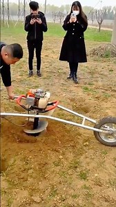 Worker operating a motorized soil auger with wheels to quickly drill deep holes in the ground