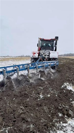 THE TRACTOR IS PLOWING THE SNOWY LAND
