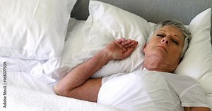 Senior woman sleeping on bed in bedroom