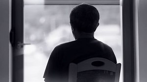 Man watching through window. Person silhouette alone sitting on chair and watching through window with landscape view.