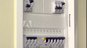 Hand checking and turning on circuit breakers in electrical fuse box at his house