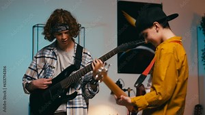 Two teenage boys playing electric guitars at home, jamming together, boys band