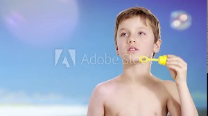 Boy at beach blowing bubbles