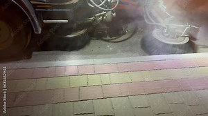 A street-cleaning machine works on a road with a lot of dust. The sweeper is working. A special machine (sweeping machine) sweeps the streets with a special brush