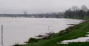 Muddy river overflowing after heavy rain, flooding the grassy riverbank