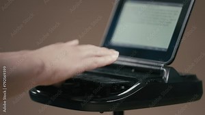 Court reporter typing on stenographer machine with out of focus screen in background