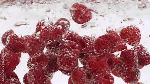 Raspberries Splashing into the Water in Slow Motion. Heap of Raspberries Falling Slowly Isolated on a White Background. Fresh water with Berries