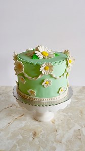 Deslumbrante pastel con margaritas todo decorado en fondant y el detalle de guirnaldas con margaritas lo hace original. 🌼🎂 #flowerscake #fondantcake #daisycake #birthdaycake #cakedecumpleaños #floresdefondant | Cookies Cupcakes De Chari