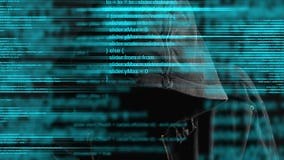 Faceless hooded anonymous computer hacker with programming code from monitor