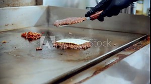 4K Cinematic food cooking footage of a chef preparing and making a delicious homemade burger in a restaurant kitchen in slow motion by flipping the burgers