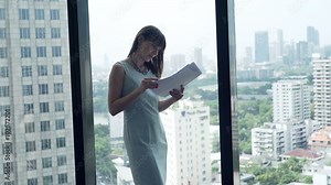 Young businesswoman reading documents by window in office