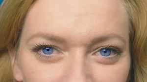 Beautiful blue eyes close-up. A young woman is blinking and is looking at the camera. 4k, close-up, slow-motion