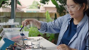 Asian woman tests analog dissolved oxygen sensor functionality with smartphone app, Agriculture and aquaculture, Internet of Things (IoT)