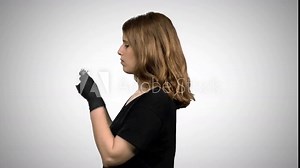 Woman demonstrating the use of a surgical mask: Putting on, coughing and sneezing, using gloves. Medium shot over white background.