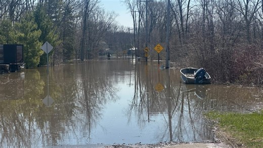Neighbors paddle down flooded street along Grand River