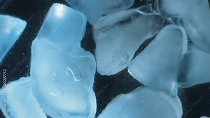 The movement of pieces of ice crystals with blue illumination on a black background. Frozen ice background. Up close