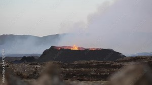 Wide shot of Litli Hrutur Volcano exploding and spewing lava during eruption with rising smoke in Reykjanes, Iceland