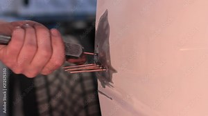 Slide hammer pulling out dents on a truck inside an automotive repair shop.