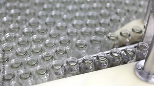 creative close up of empty glass vial bottles moving on a conveyor belt in two rows. medical Injection making process ampoules in a pharmaceutical manufacturing production medicine factory