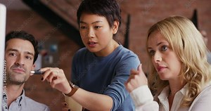 a group of businesspeople using a computer in a modern office. Diverse group of businesspeople working together in a meeting, collaborating and planning using a computer. Colleagues talking at work
