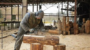 Construction worker planing a piece of wood for a building project. Construction grinds electric hand plane. Against the background of the factory premises, slow motion