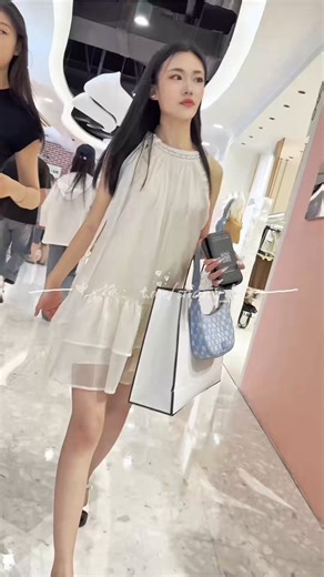 整个商场，仿佛被她一人点亮。她仙气飘飘，像从云端误入凡尘的精灵。细白修长的大长腿，踩着精致的小高跟，每一步都优雅轻盈，踩出了夜色的节奏。那张甜美到让人心颤的脸蛋，带着柔软的笑意，轻轻一瞥便足以让人失神。整个商场都因她而明亮了几度。路过的目光全被她吸走，我又怎能例外？心跳不由自主地加速，这份心动来得如此自然，又如此强烈。我悄悄记录下她每一秒的瞬间——裙摆轻晃的弧度、发丝拂过的温柔、回眸时的惊艳……全都深深刻进眼里，也偷偷藏进了心底。她一出现，夜色都变得浪漫了。