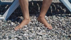Kid teen sits on sun loungers on the beach playing with his feet on the stones. concept of vacation, recreation, travel with children