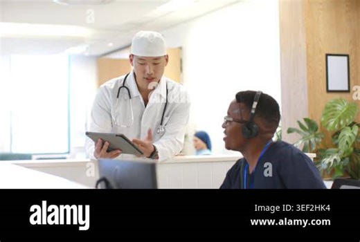 Asian doctor approaching desk, consulting African American staff, showing tablet, confirming info. Clinical, collaboration, communication, healthcare, clinic, stethoscope, teamwork Stock Video Footage - Alamy