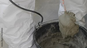 Adhesive mix for tiles in a black bucket. Tile adhesive is mixed using an electric drill in a bucket.