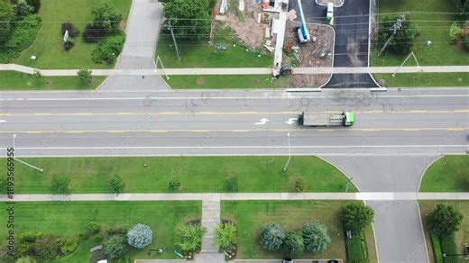 Aerial view tracking backwards from a residential street to reveal a new commercial building construction site with a drive thru lane, situated next to an industrial park area