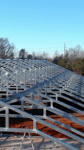 Workers construct metal beams roof framework in construction site
