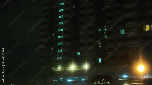 Camera video of high-rise building at night with illuminated windows and street lights