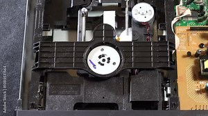An open DVD player shows its internal components and circuitry, with the disc loading and unloading movements, seen from several angles. This image highlights the technology and design of home enterta