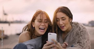 Two girls laughing together after taking some photos on a sunny day