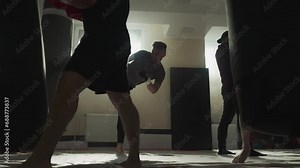 Fighters team exercise with punching inventory in sports club. Kick-boxers do kicks and punches in fighting gym slow motion. Combat techniques
