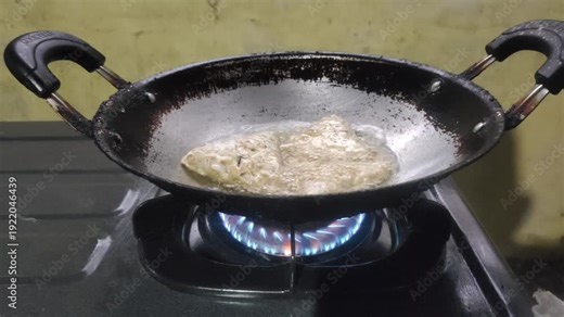 The process of deep-frying tempeh using hot oil in a frying pan.