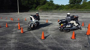 Officer Russell and Officer Heist navigate a riding training exercise affectionately known as "The Snowman" which is three decreasing radius turns which requires the officers to manage throttle and clutch control while placing emphasis on motorcycle placement to avoid hitting the cones. | Plant City Police Department
