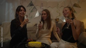 Trio of happy girlfriends clink glass of champagne and rejoice during bachelorette party celebration at home in the evening
