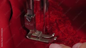 Close-up of a seamstress sewing a red openwork fabric to a dress in an atelier. The process of sewing an evening dress.