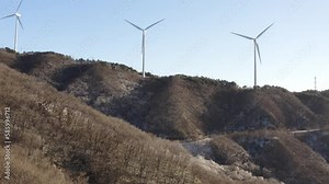 Modern windmills with turning blades on hills under a clear sky