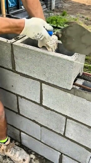 Installing concrete blocks on a wall with skill, creating a strong, neat, and well aligned structure