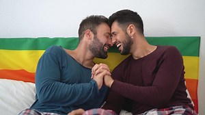 two men laughing and smiling in bed
