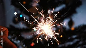 Firework sparkler burning with lights in background in slow motion