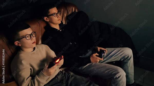 teenagers play games on joysticks at night, two boys holding gamepads and playing a computer game, happy friends playing together, entertainment, virtual world, internet addiction, gamer