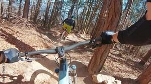 A POV point of view shot of an MTB mountain biker riding a bike on trails in a forest.